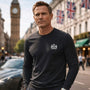 Man wearing a James Bond black long-sleeve shirt with a logo in an urban setting with Big Ben in the background