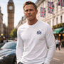 Man wearing a James Bond white long-sleeve shirt with a logo in an urban setting with Big Ben in the background