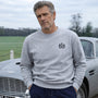 Man wearing James Bond Luxury Sweatshirt in Grey Sweatshirt standing next to Aston Martin DB