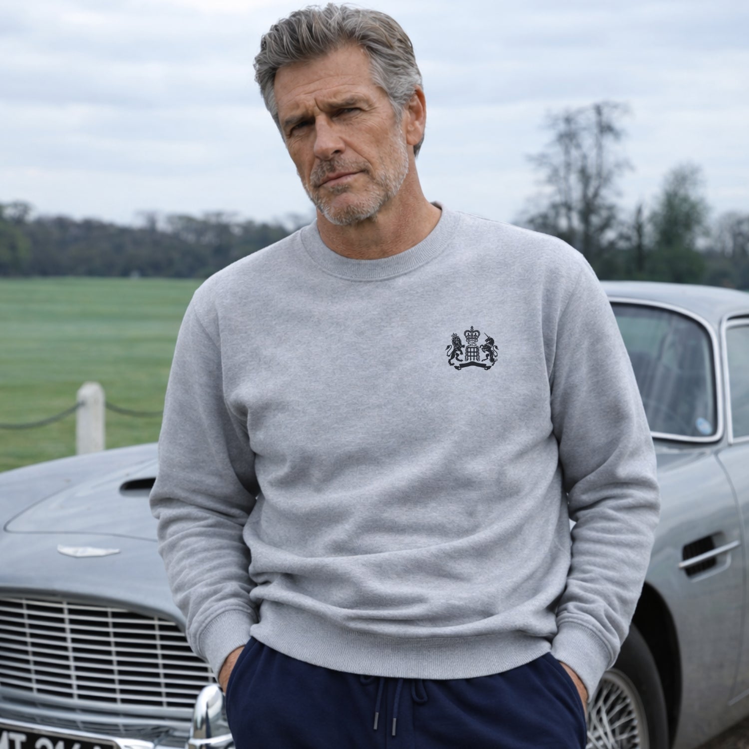 Man wearing James Bond Luxury Sweatshirt in Grey Sweatshirt standing next to Aston Martin DB