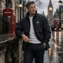 Man in Navy jacket standing on a rain-soaked street with iconic London landmarks in the background