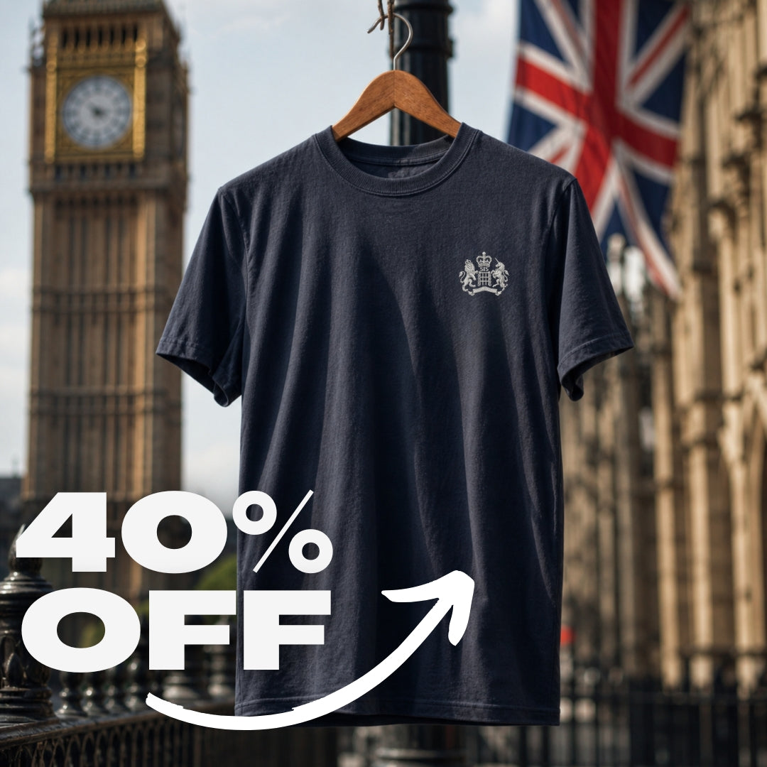 A James Bond inspired navy blue short-sleeve t-shirt with a small white S.I.S. Logo embroidered on the left chest, hanging on a wooden hanger against a blurred background of Big Ben and a Union Jack flag. A large white '40% OFF' graphic overlay is in the foreground.