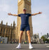 Person in athletic t-shirt standing with arms outstretched in front of Big Ben, London.