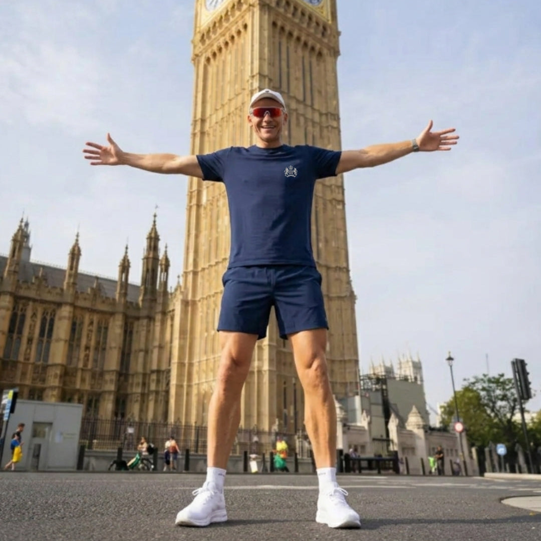 Person in athletic t-shirt standing with arms outstretched in front of Big Ben, London.