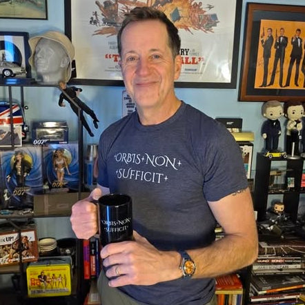 Man holding a mug in a room with James Bond posters and memorabilia
