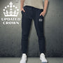 Person wearing navy jogger pants with a logo, standing against a textured gray wall with 'Updated UK King's Crown' branding.
